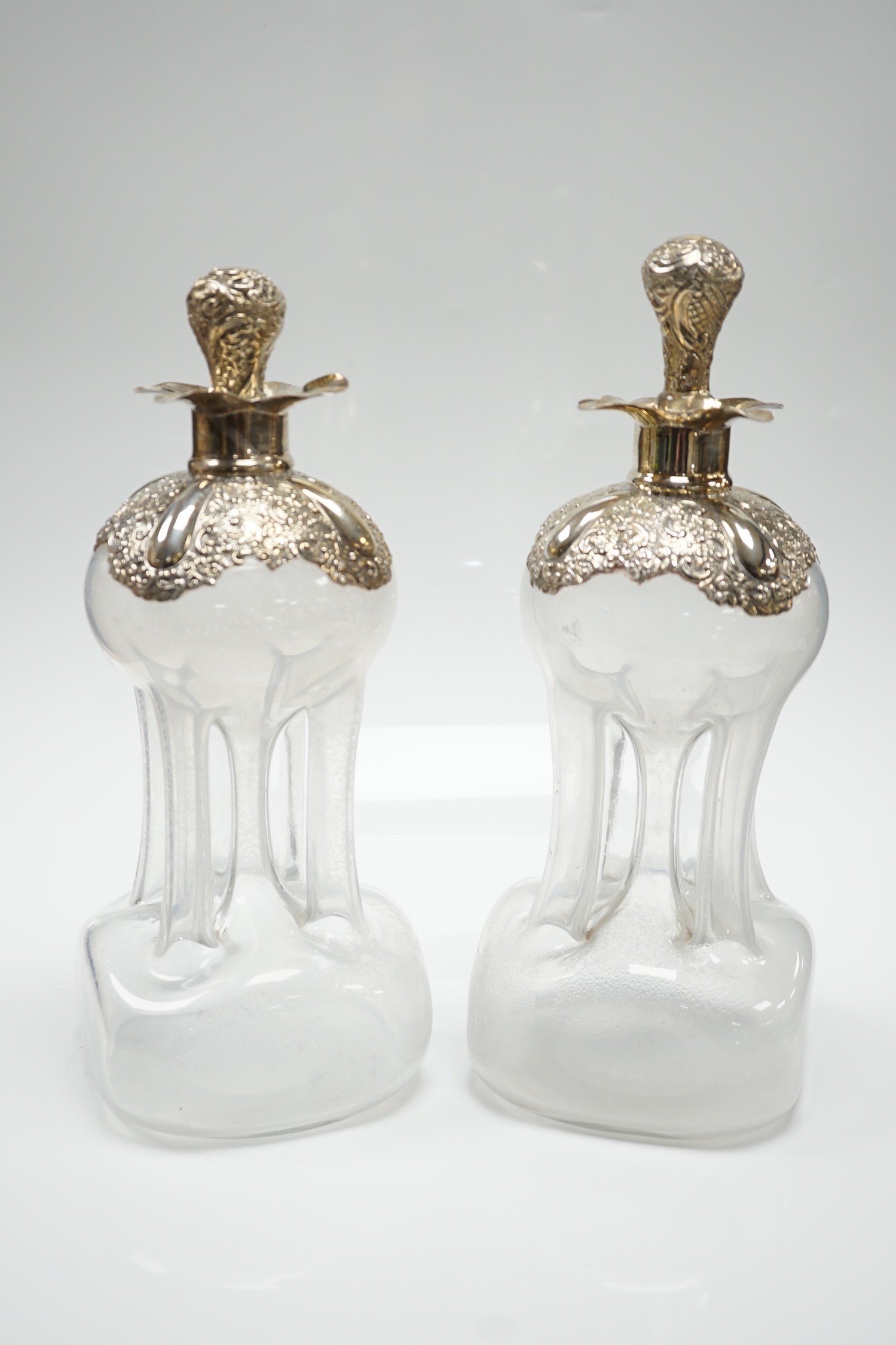 A pair of Edwardian silver mounted glass hour glass shaped decanters, William Hutton & Sons, Birmingham, 1906/7, with associated stoppers, height 23.9cm.
